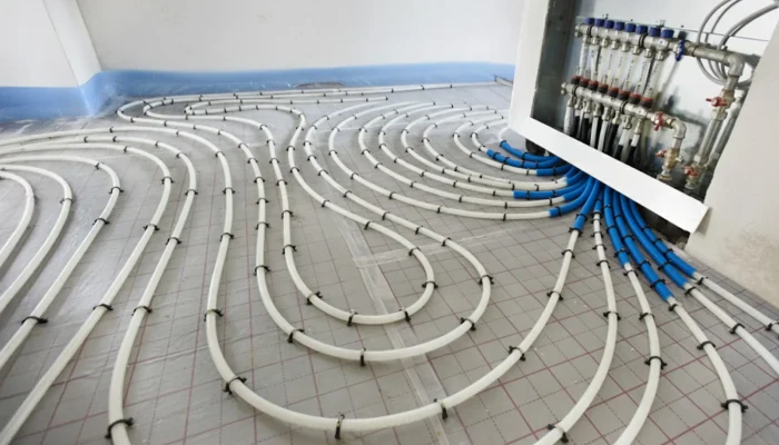 Verkabelungssystem für Fußbodenheizung mit weißen und blauen Rohren in einem modernen Raum.